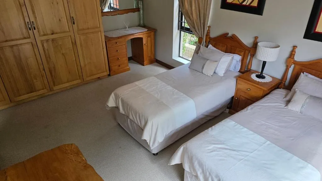 Spacious bedroom with two beds, wooden furniture, and large wardrobe