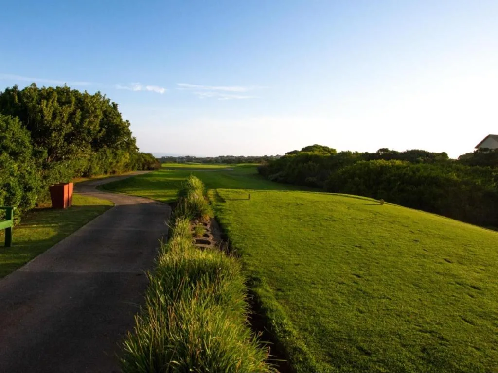 Driveway leading through manicured gardens with expansive green lawns and distant views