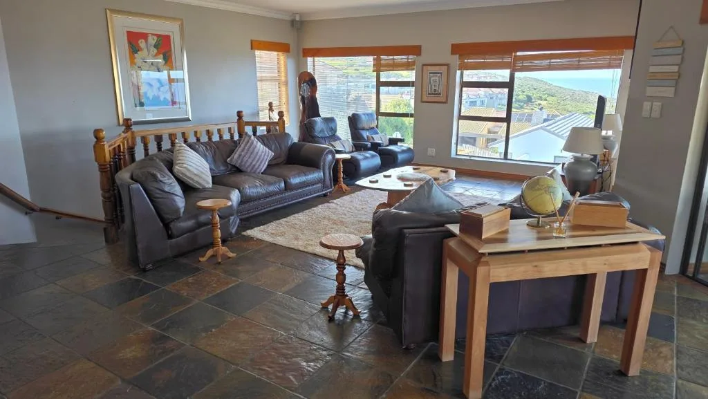 Spacious lounge with dark leather sofas and mountain views through large windows