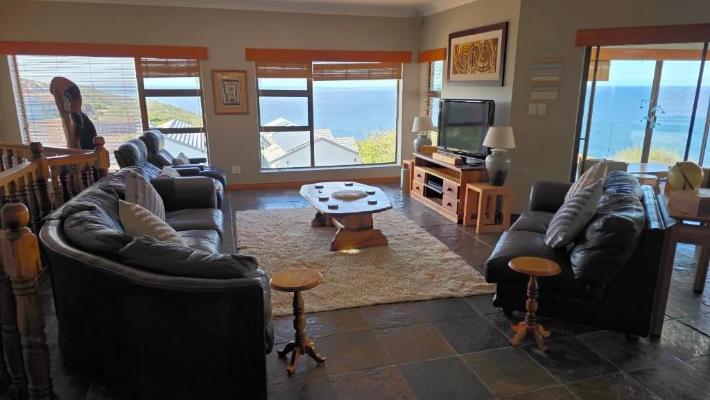 Spacious lounge with black leather sofas overlooking blue ocean views through large windows
