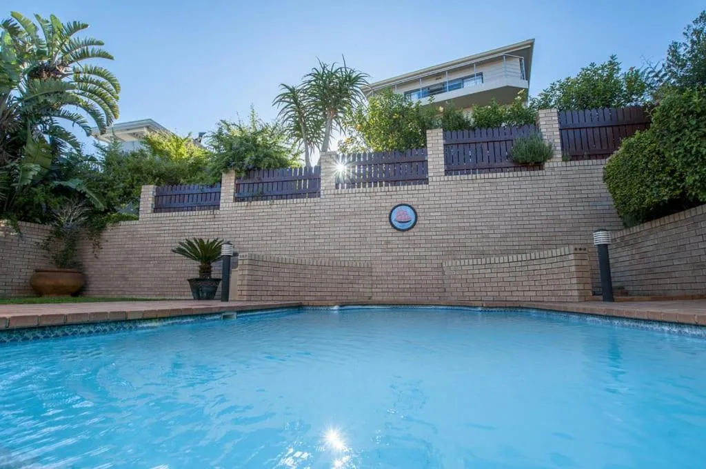 Sparkling blue swimming pool with brick facade and modern building