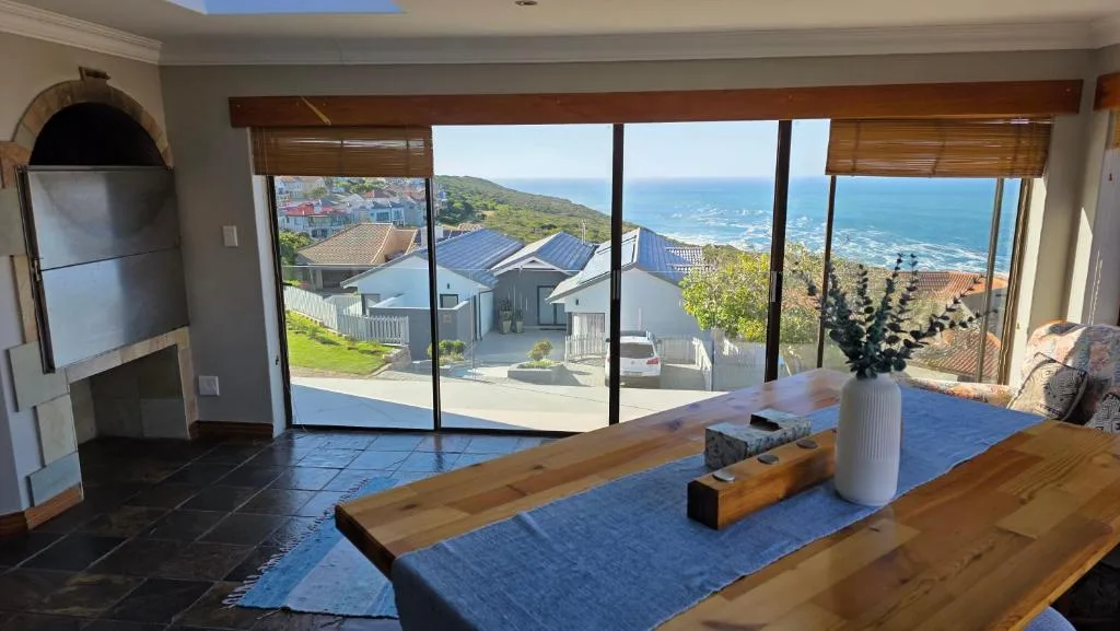 Expansive ocean and coastal mountain vista through floor-to-ceiling windows