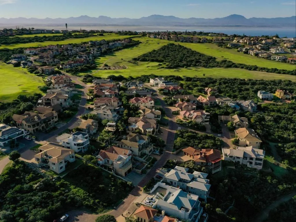 Aerial view of suburban homes with lagoon and mountains beyond