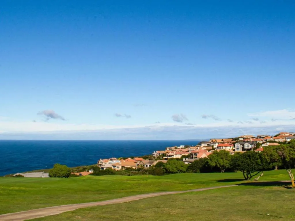 Expansive ocean and coastal suburb vista from manicured green lawn