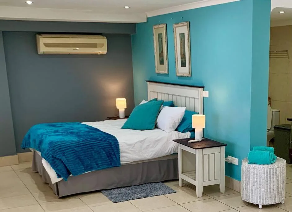 Modern bedroom with turquoise accent walls, white headboard, and blue bedding