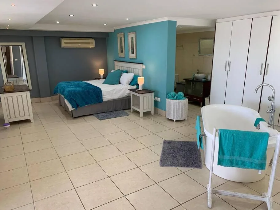 Spacious bedroom with turquoise accent wall, queen bed, and en-suite bathroom