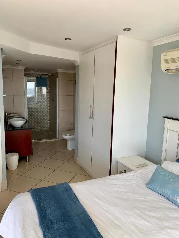 Bedroom with bed and ensuite bathroom visible through open doorway