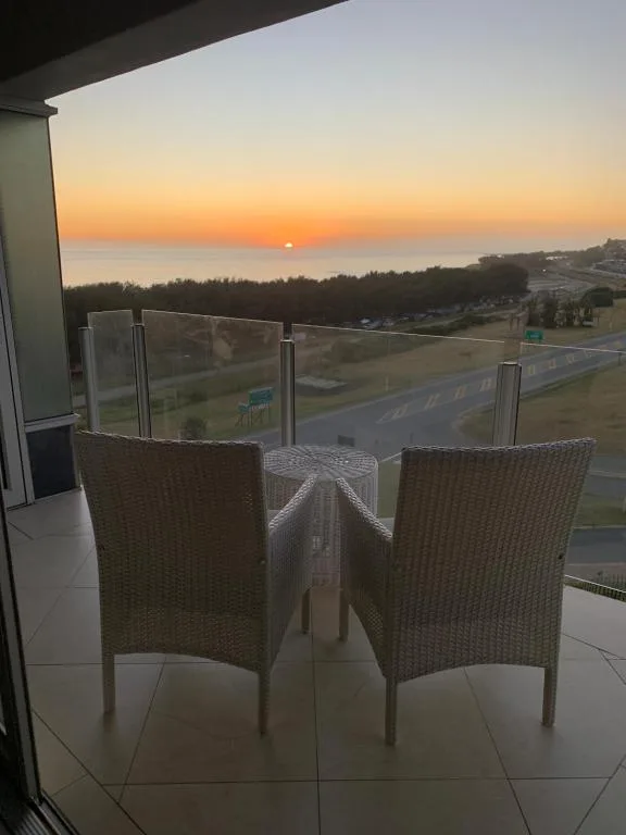 Sunset view from balcony with wicker chairs and glass railing