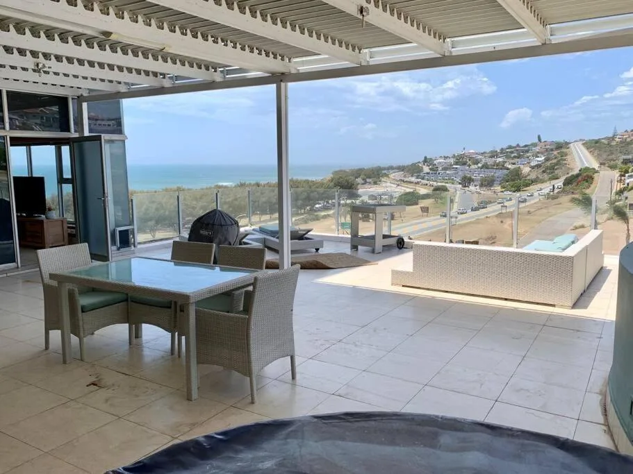 Expansive seaside deck with dining table, lounge seating, and ocean views