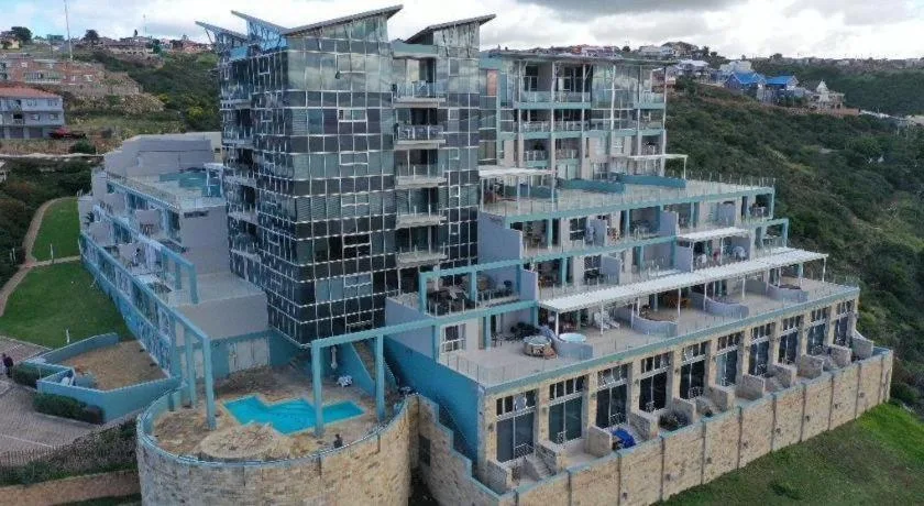 Modern multi-story residential building with glass and blue facades on hillside