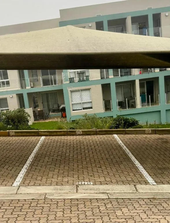 Modern apartment building facade with turquoise trim and parking area