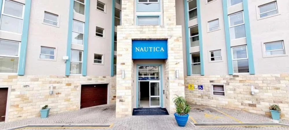 Modern apartment building entrance with blue signage and stone facade