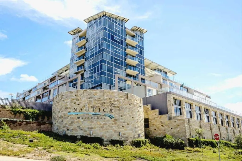 Modern multi-story residential building with stone facade and glass balconies