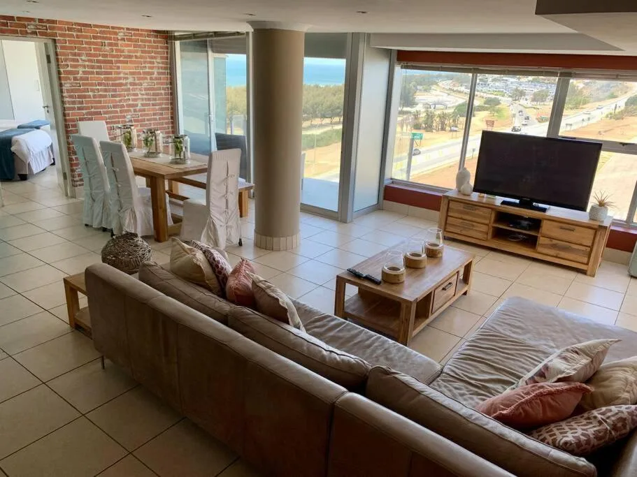 Spacious living room with sofa, TV, dining area and expansive sea views