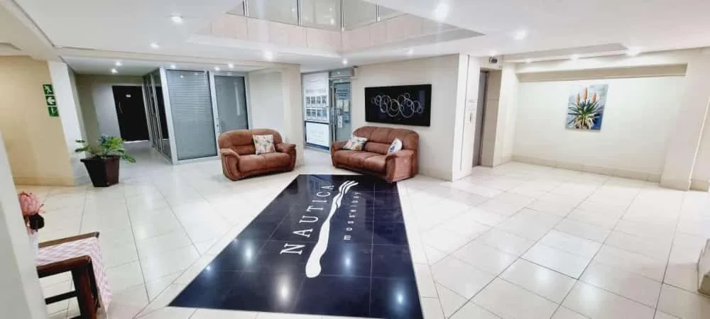 Modern lounge with twin brown sofas, polished tile floors, and contemporary wall art