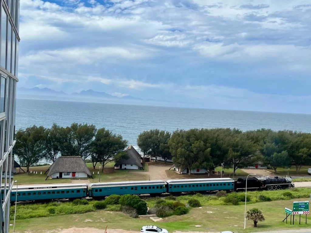 Scenic coastal vista with ocean, mountains, and heritage train display