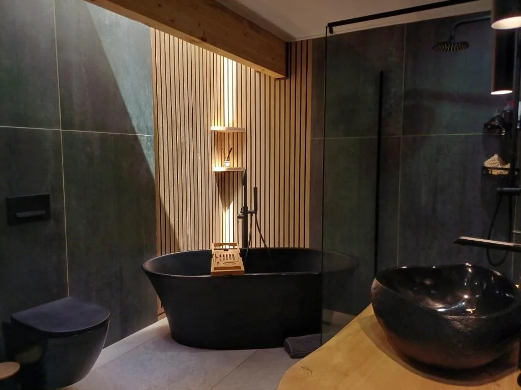 Modern bathroom with black freestanding tub and wooden accent wall