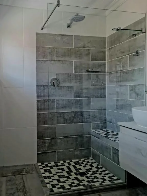 Modern shower enclosure with gray tile and black-and-white floor pattern