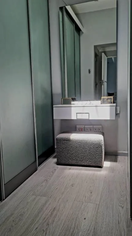 Modern bathroom with white vanity, large mirror, and gray pouf seating