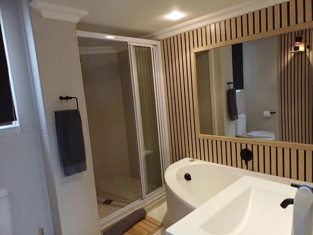 Modern bathroom with freestanding bathtub, rainfall shower, wooden accent wall