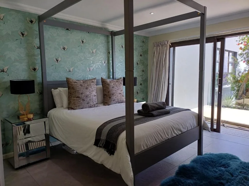 Elegant four-poster bed with botanical wallpaper and garden view doors