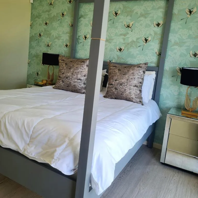 Modern bedroom with four-poster bed, white bedding, and botanical wallpaper