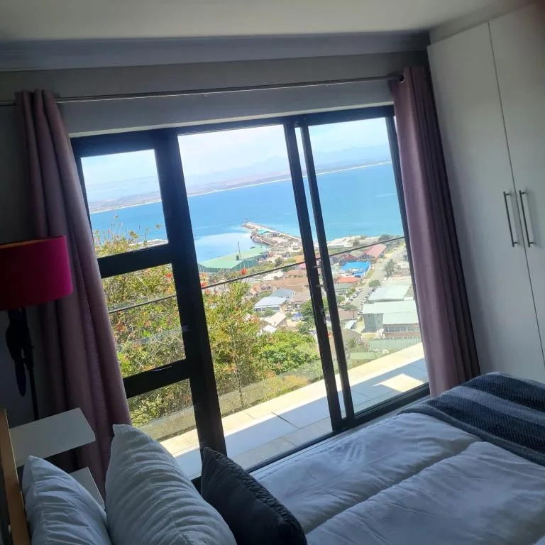 Bedroom with bed facing glass doors overlooking coastal sea view
