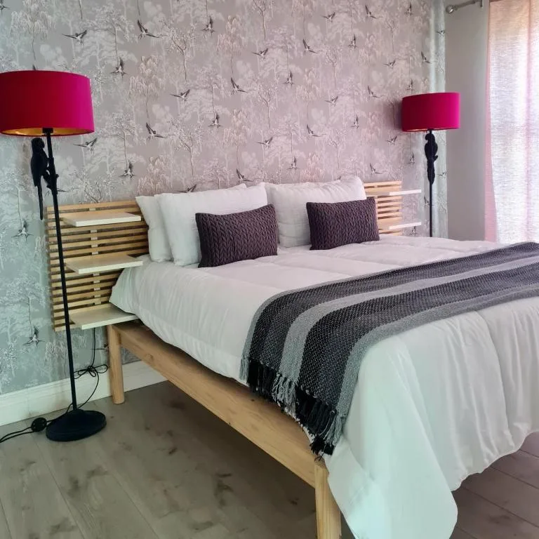 Modern bedroom with wooden bed, pink patterned wallpaper, magenta lamps