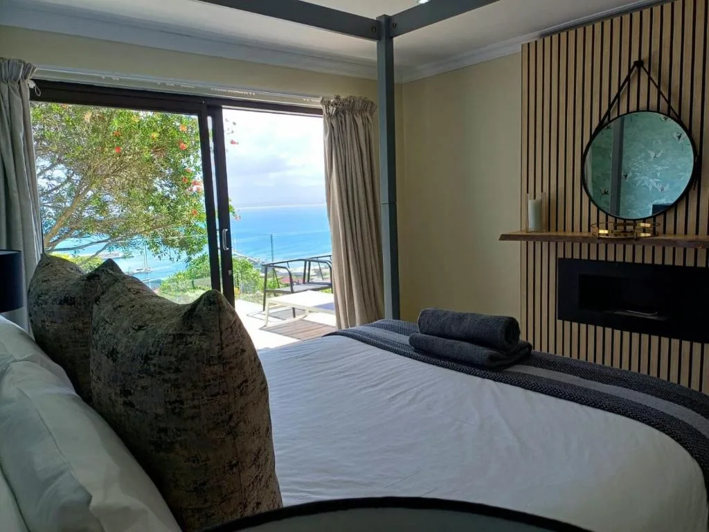 Bedroom with ocean view through sliding glass doors and coastal deck access