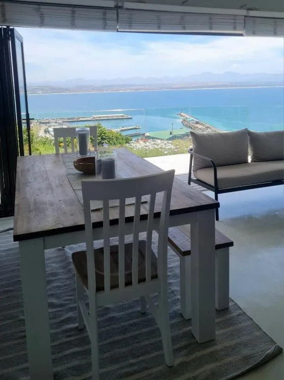 Elevated deck with dining table and ocean views over Mossel Bay