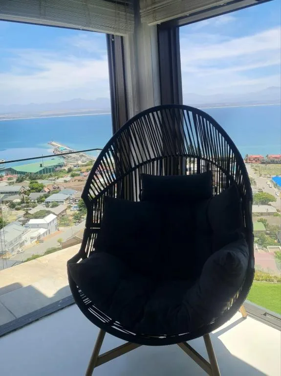 Black egg chair on balcony overlooking Mossel Bay coastal landscape