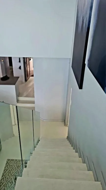 Modern staircase with glass railing leading upstairs in bright interior