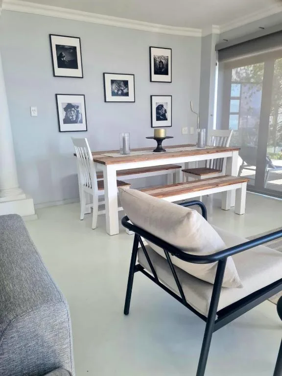 Modern dining area with wooden table, white chairs, and framed artwork