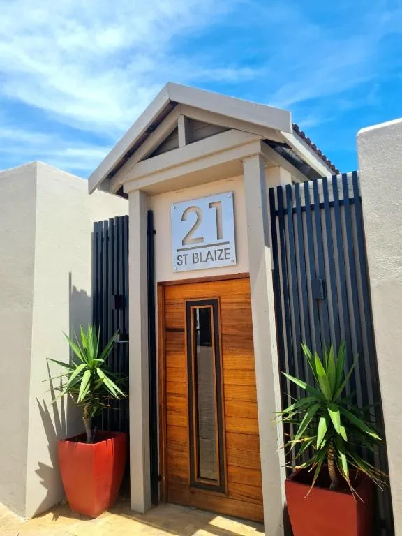 Modern beach house entrance with wooden door and potted plants
