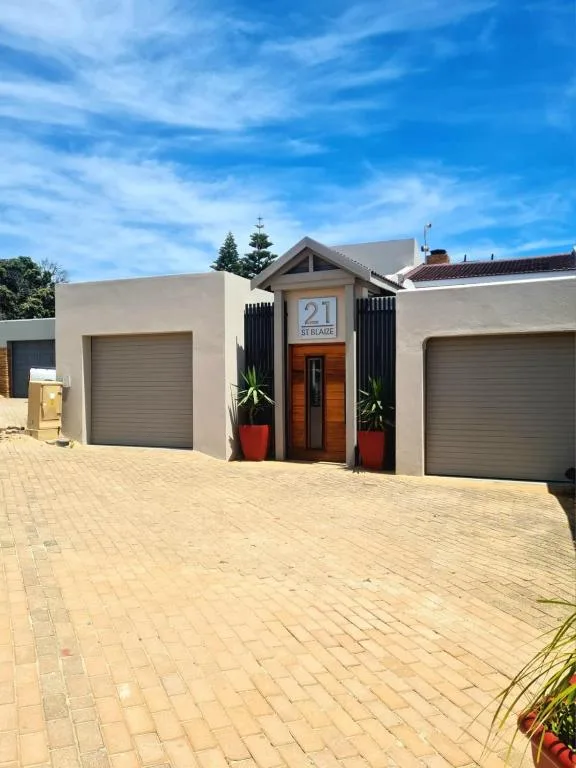 Modern white cottage with double garage doors and welcoming entrance on paved driveway