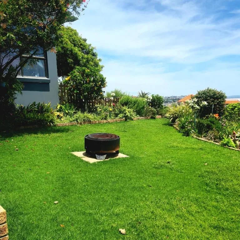 Lush green garden with fire pit, landscaping, and scenic views beyond