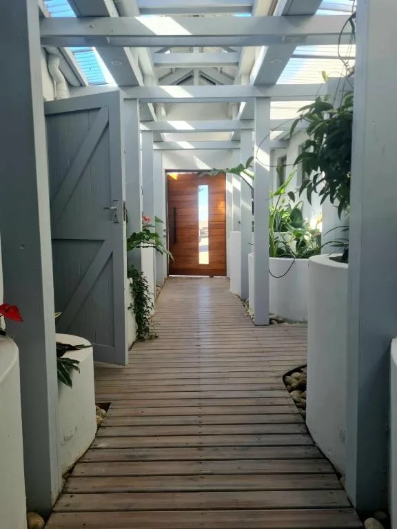 Modern white pergola entrance with wooden door and potted plants