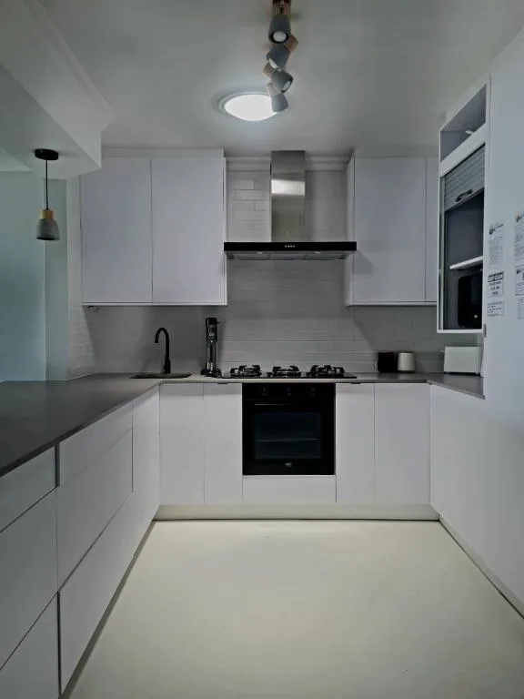 Modern white kitchen with black gas stove and sleek cabinetry