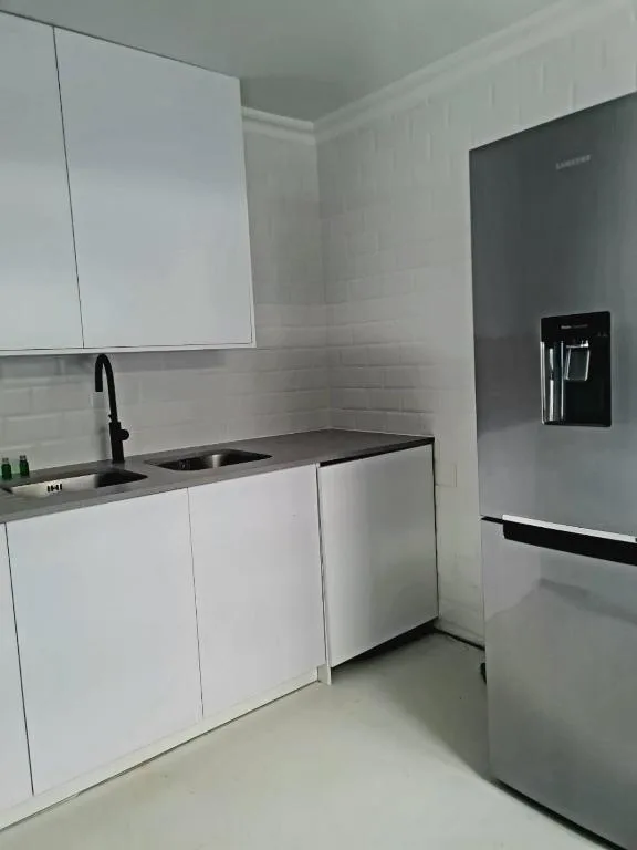 Modern white kitchen with black sink, stainless steel appliances, and cabinetry