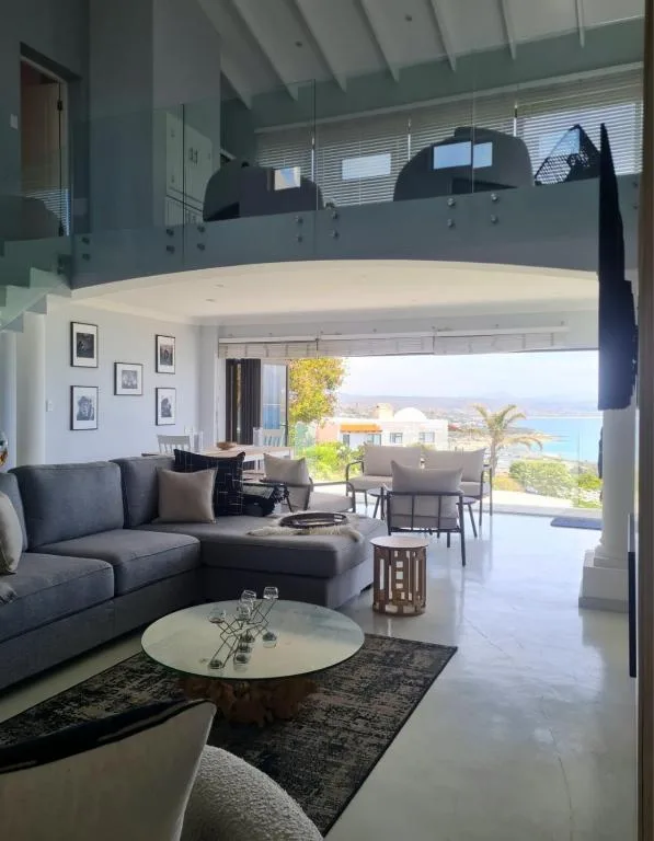 Modern lounge with curved sofa, glass coffee table, ocean view beyond