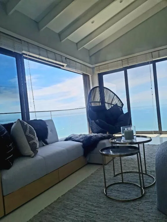 Lounge with coastal views, seating, and hanging chair by windows
