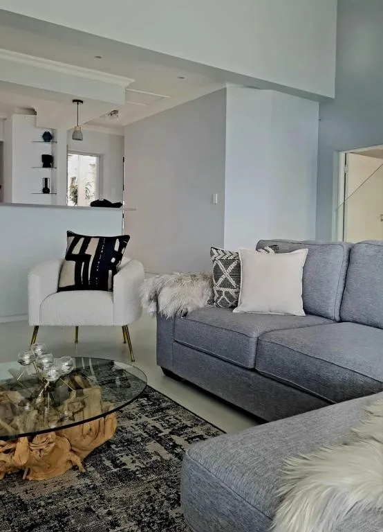 Modern lounge with gray sofa, white armchair, and glass coffee table