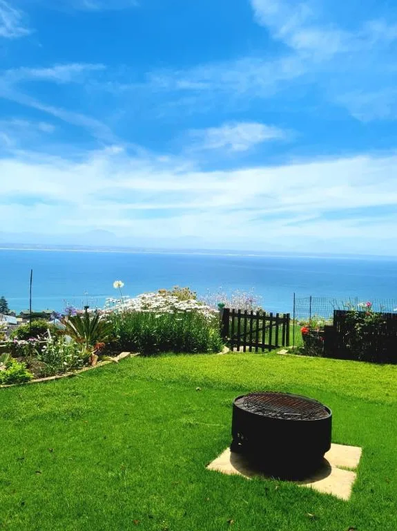 Expansive ocean view from manicured garden with braai pit overlooking coastal town