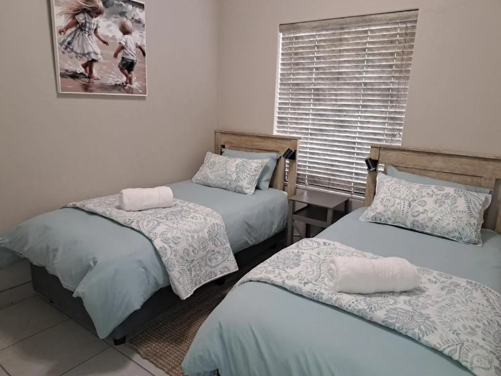 Twin bedroom with wooden headboards, blue bedding, and patterned pillows
