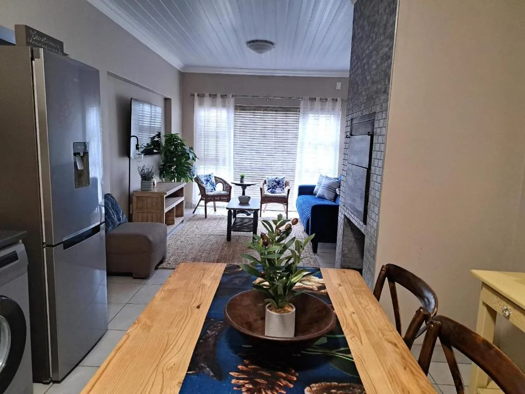 Wooden dining table with potted plant, open-plan kitchen and lounge beyond