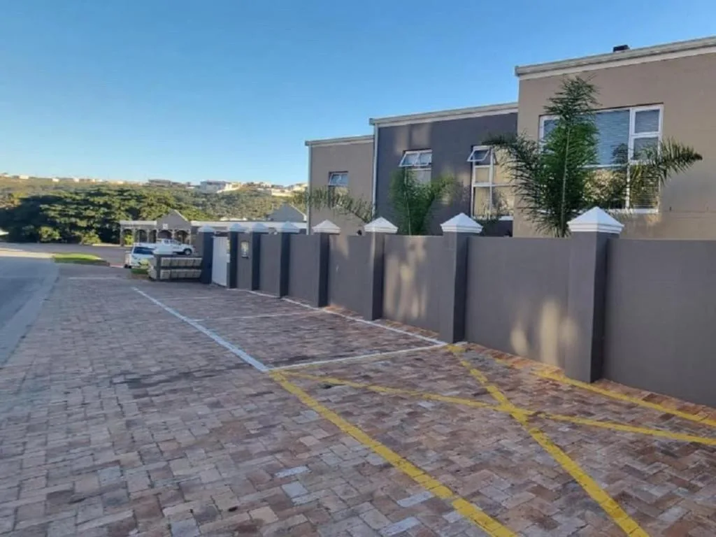 Modern townhouse exterior with paved driveway and landscaped entrance garden.