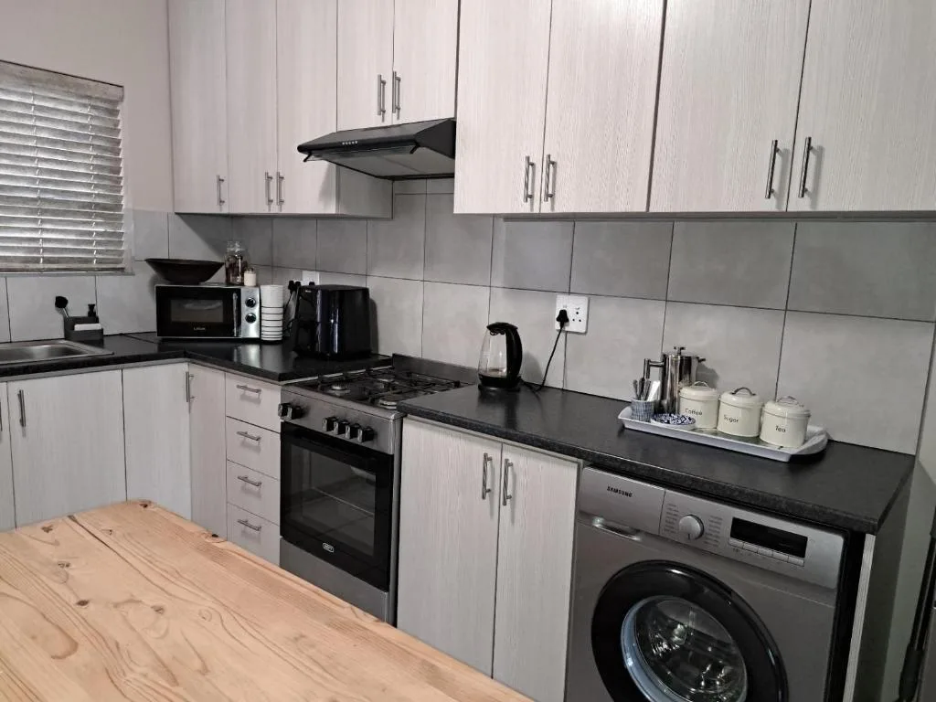 Modern kitchen with white cabinetry, black countertops, gas stove, and washing machine