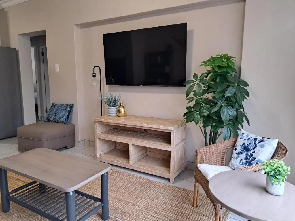 Modern lounge with wall-mounted TV, wooden media console, and comfortable seating