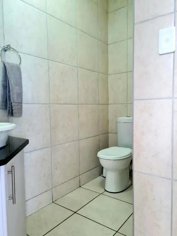 Bathroom with cream tiles, toilet, vanity sink, and towel rack