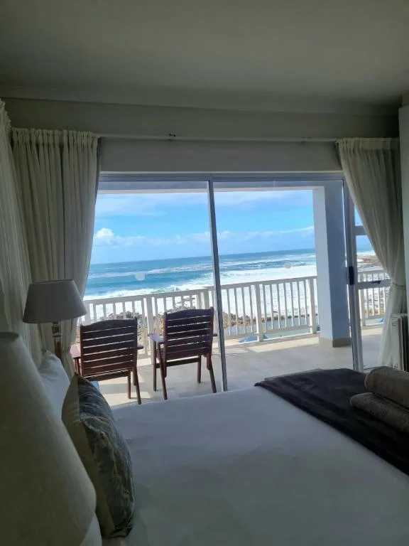 Bright bedroom with ocean view through glass doors and white railing
